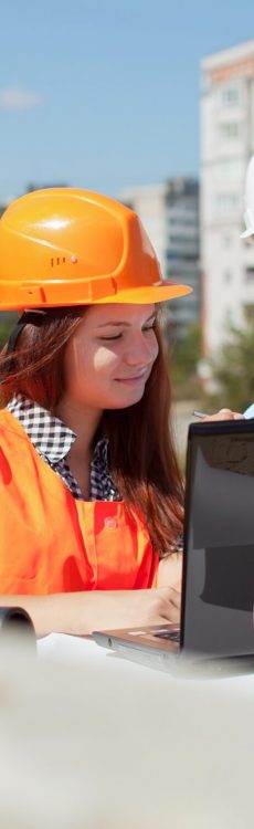 Two architects wearing protective helmet standing in front of building site