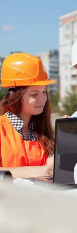 Two architects wearing protective helmet standing in front of building site